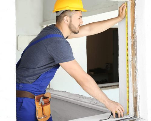 worker measuring window opening for replacement window installation